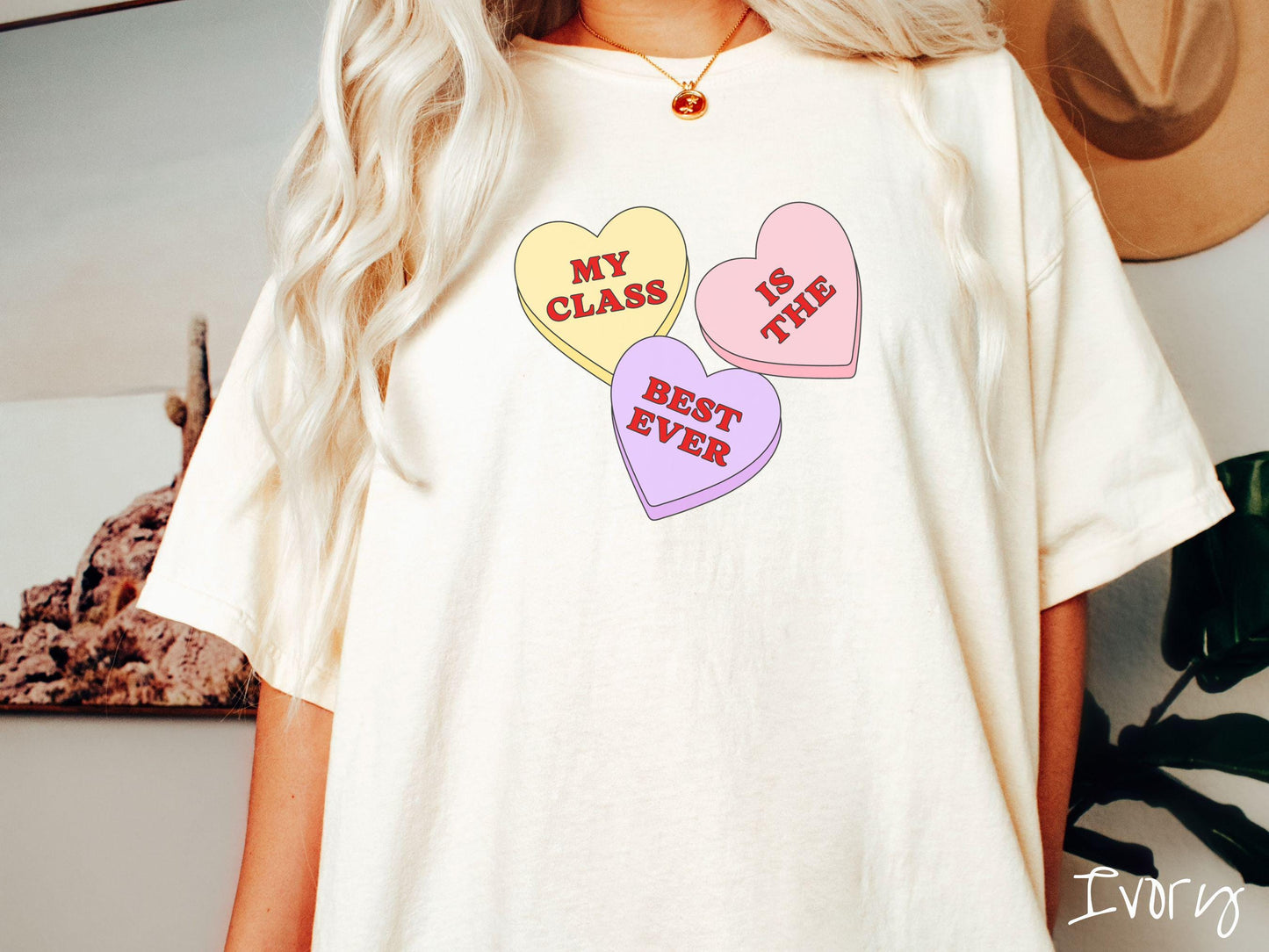 A charming vintage-style Valentine’s Day Comfort Colors t-shirt featuring three vibrant conversation hearts in yellow, red, and purple, this design displays the text “My class is the best ever” spread across the hearts.