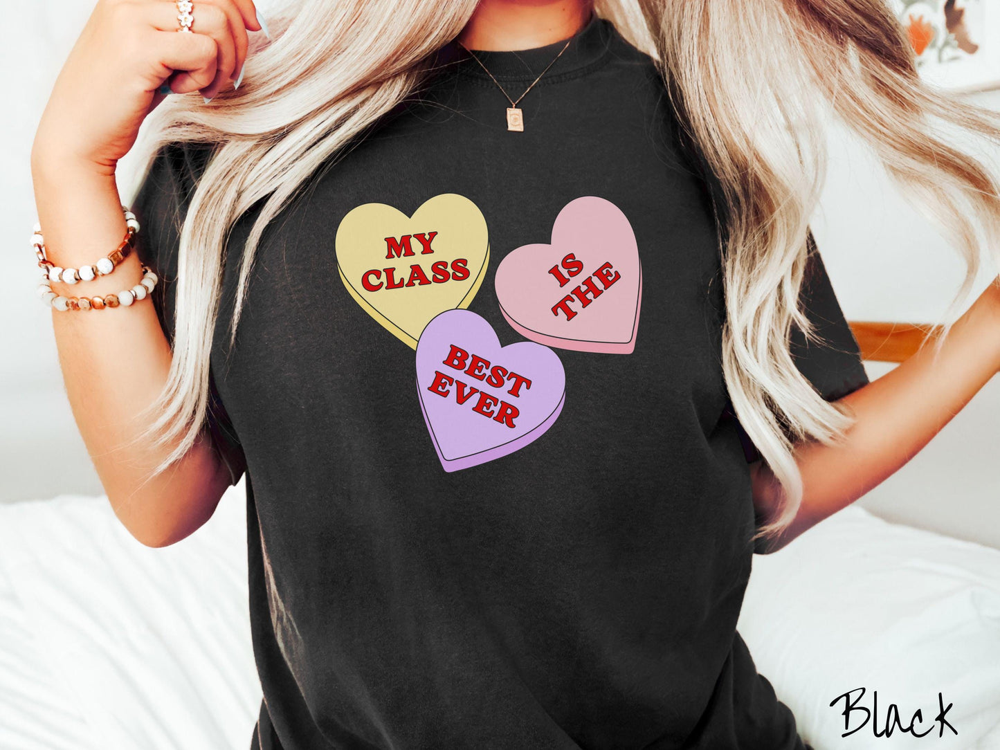 A charming vintage-style Valentine’s Day Comfort Colors t-shirt featuring three vibrant conversation hearts in yellow, red, and purple, this design displays the text “My class is the best ever” spread across the hearts.