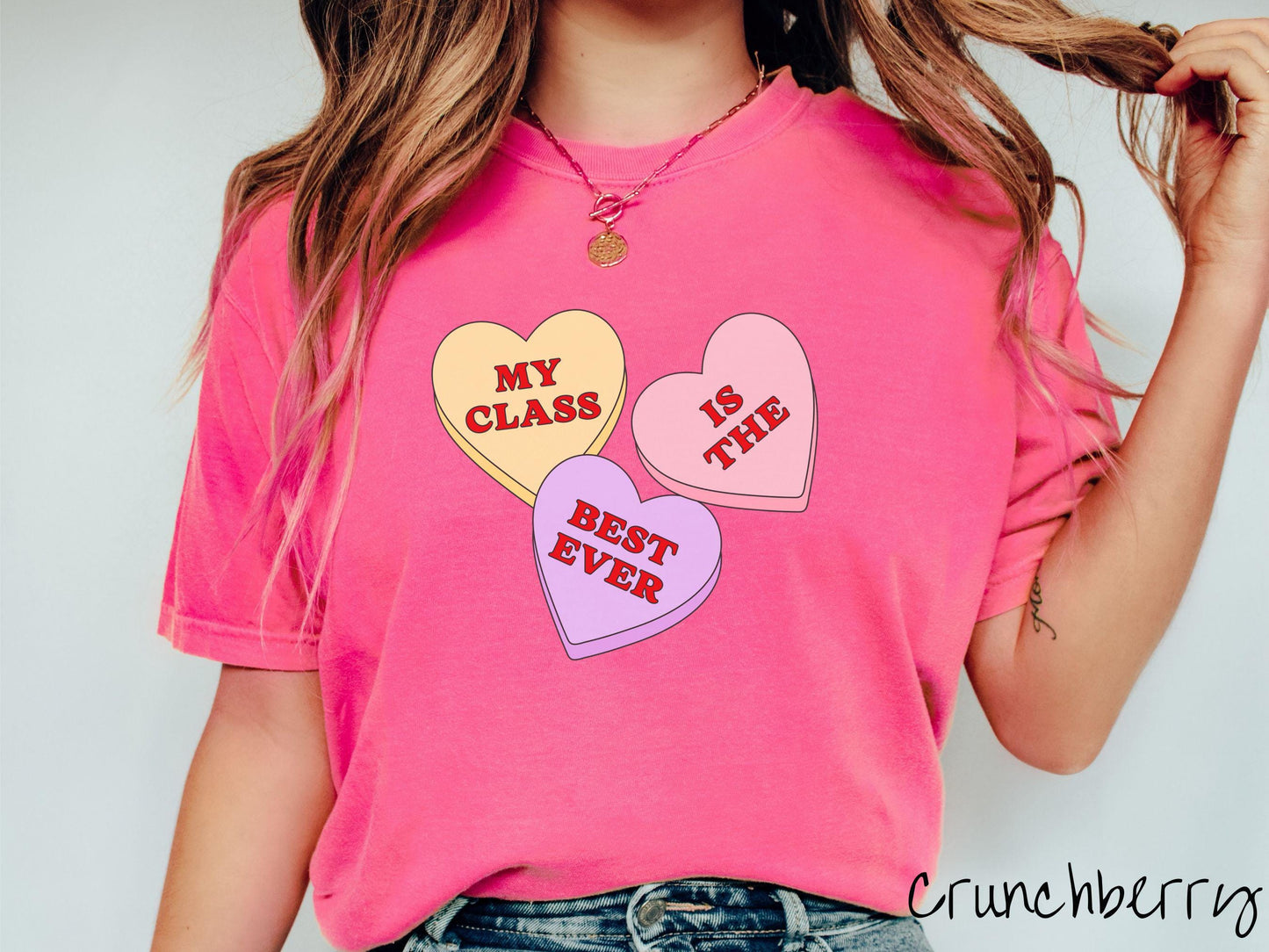 A charming vintage-style Valentine’s Day Comfort Colors t-shirt featuring three vibrant conversation hearts in yellow, red, and purple, this design displays the text “My class is the best ever” spread across the hearts.