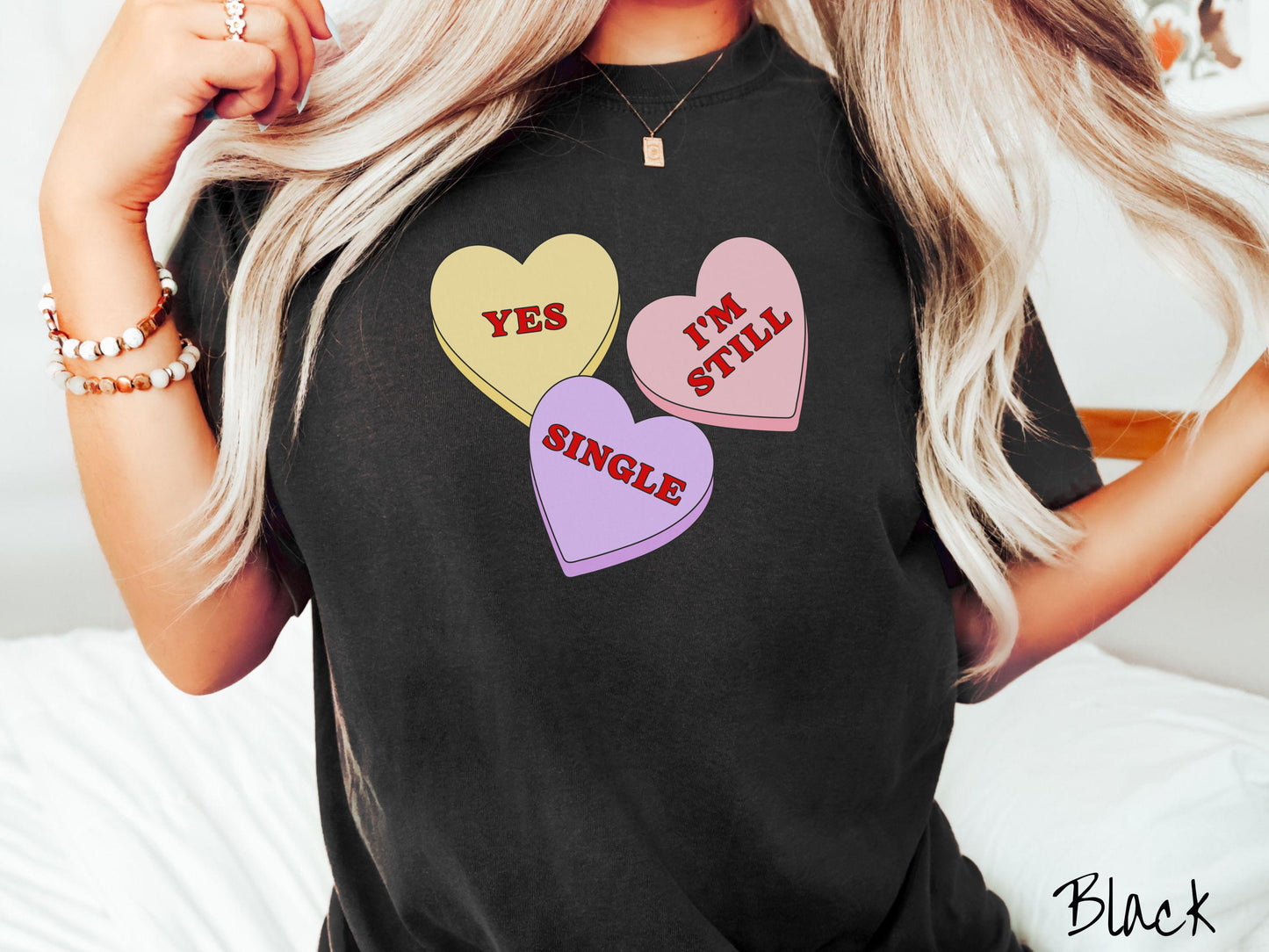 Make a bold statement this Valentine’s Day with this vintage Comfort Colors t-shirt featuring three vibrant conversation hearts in yellow, red, and purple, the design showcasing the cheeky phrase “Yes, I’m Still Single” spread across the hearts.