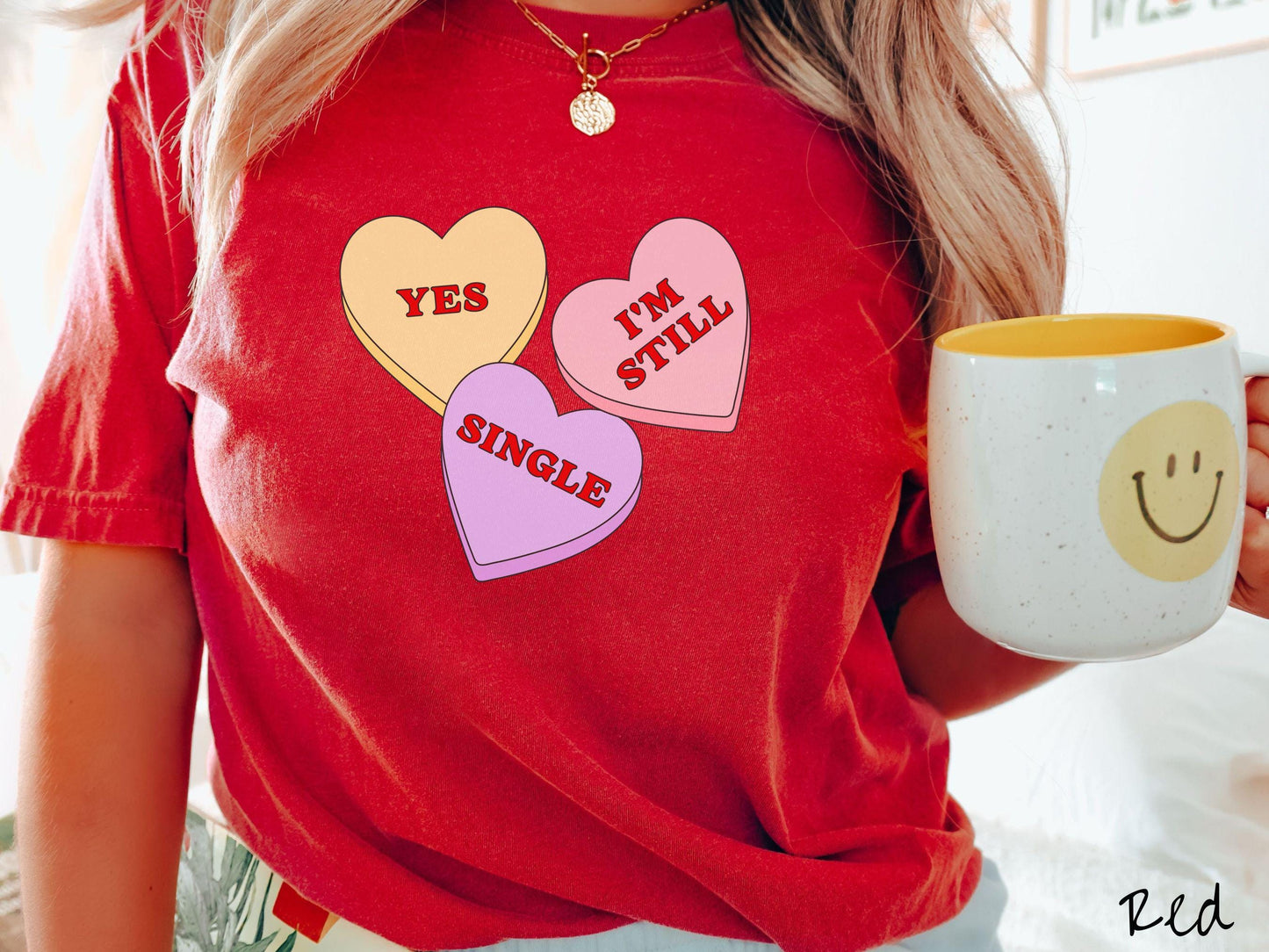 Make a bold statement this Valentine’s Day with this vintage Comfort Colors t-shirt featuring three vibrant conversation hearts in yellow, red, and purple, the design showcasing the cheeky phrase “Yes, I’m Still Single” spread across the hearts.