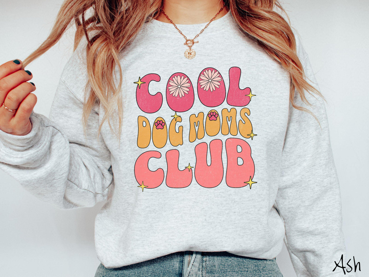 A vintage Gildan sweatshirt featuring the playful text Cool Dog Moms Club, this design is full of charming details. From flower petals nestled in the "O" of COOL to a cute red paw print in the "O" of DOG and sparkling yellow stars throughout.