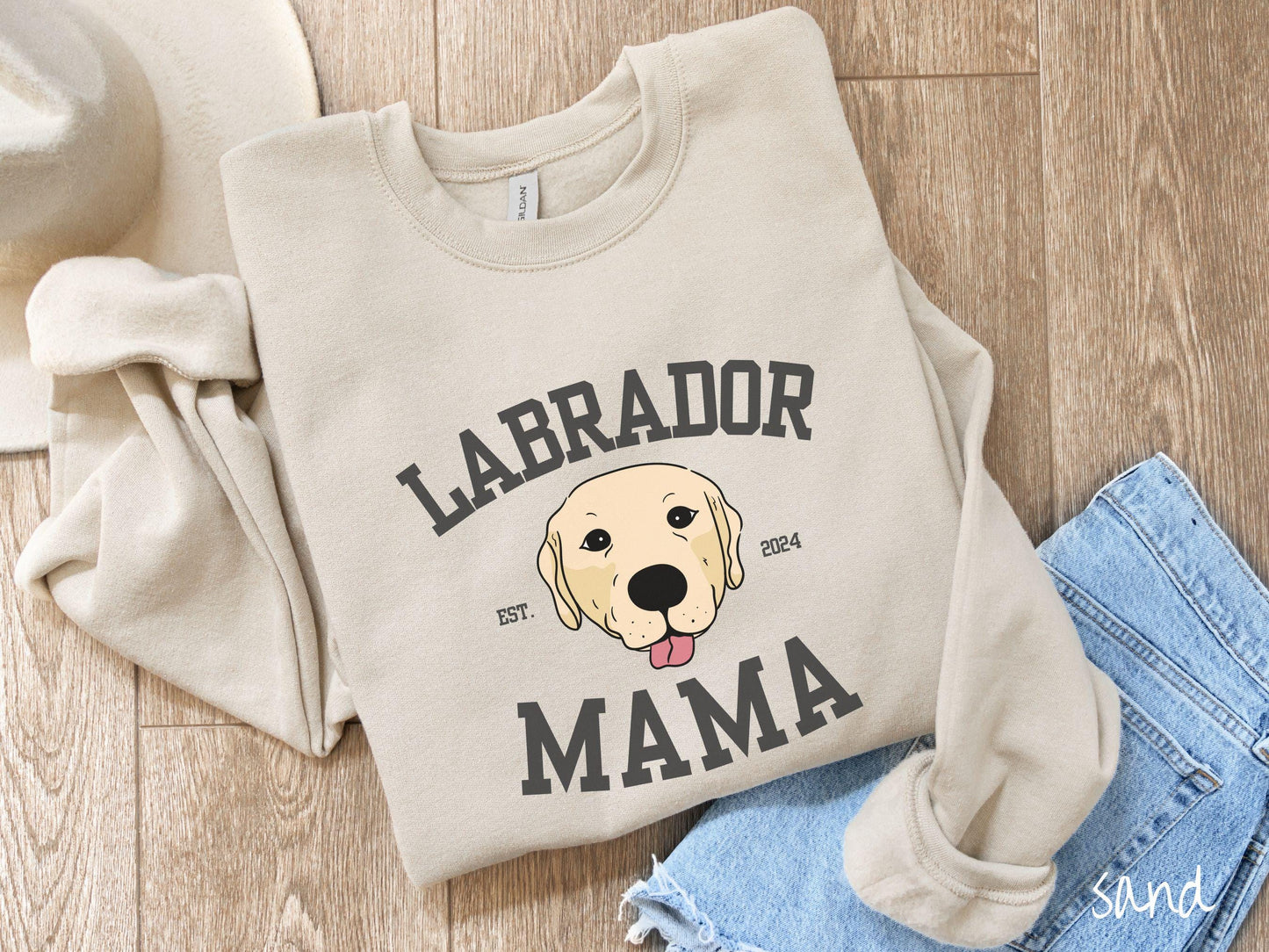 A vintage Gildan sweatshirt featuring bold block lettering that reads 'Labrador Mama.' At the center of the design, a playful yellow Labrador with its tongue out steals the spotlight, framed by the stylish text 'EST. 2024.'
