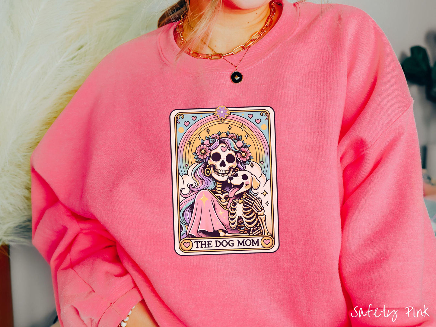 A vintage Gildan sweatshirt features a tarot card design with the text “The Dog Mom” along the bottom, framed by red hearts. Inside the tarot card is a female skeleton with flowing hair adorned with colorful flowers holding a skeleton dog.