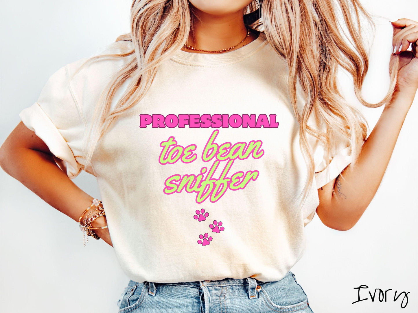 A vintage Comfort Colors t-shirt perfect for dog lovers who can’t resist those adorable toe beans! It features the funny text Professional Toe Bean Sniffer in bold pink and green fluorescent font, and below the text are three pink dog paw prints.