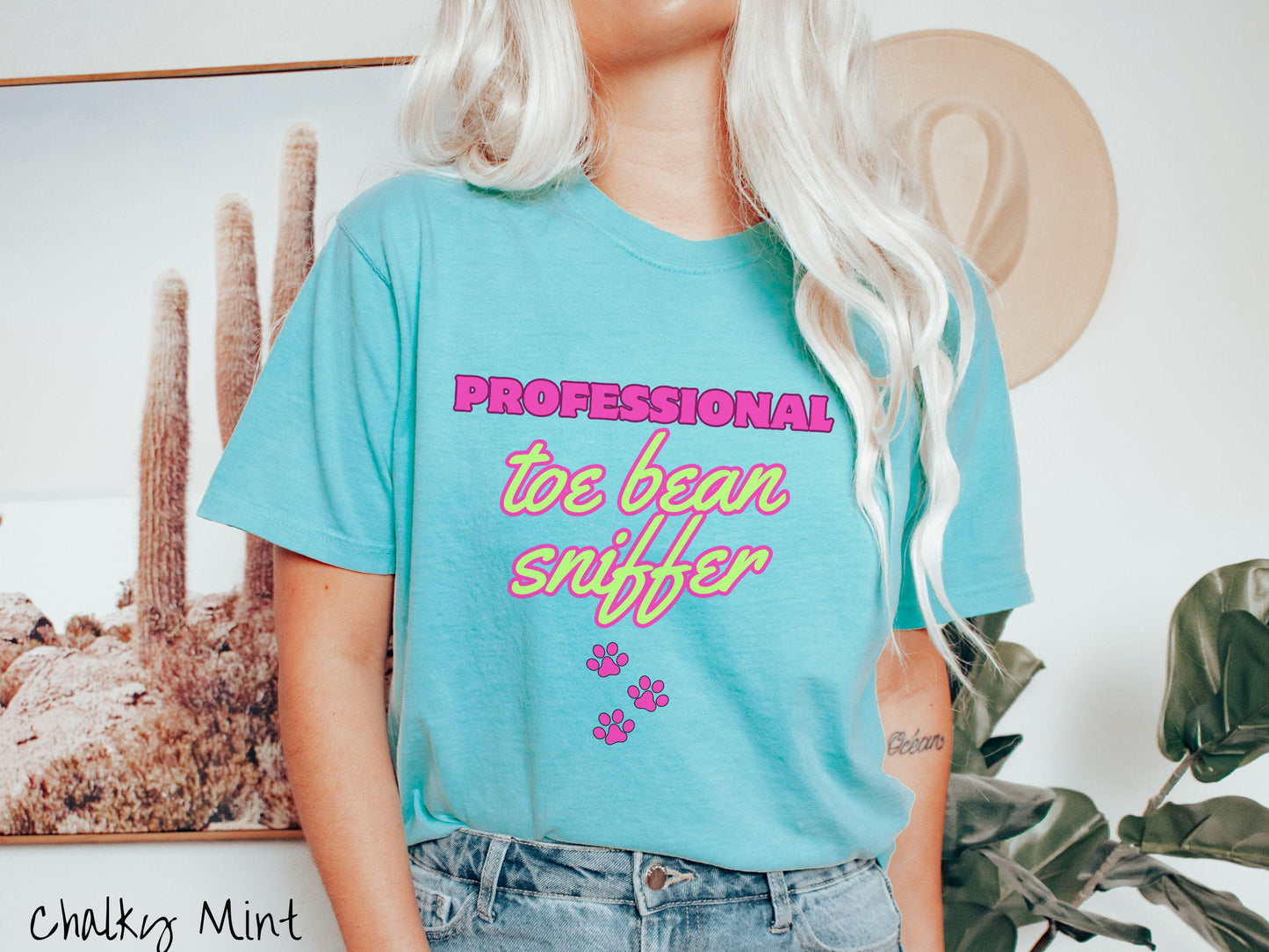 A vintage Comfort Colors t-shirt perfect for dog lovers who can’t resist those adorable toe beans! It features the funny text Professional Toe Bean Sniffer in bold pink and green fluorescent font, and below the text are three pink dog paw prints.