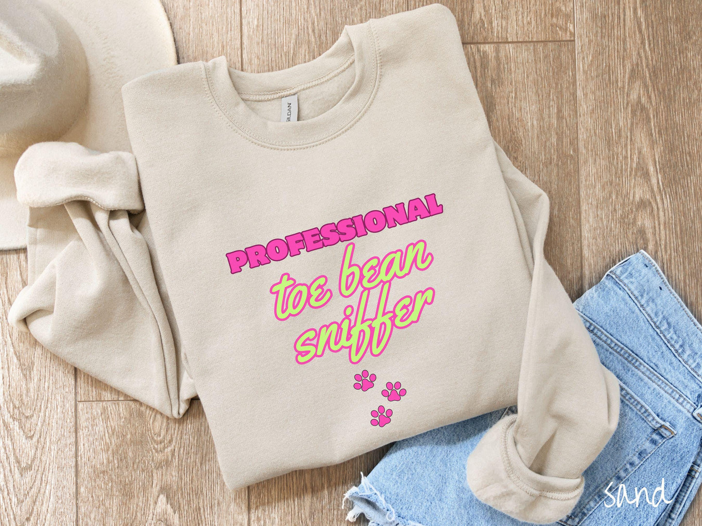 A vintage Gildan sweatshirt perfect for dog lovers who can’t resist those adorable toe beans! It features the funny text Professional Toe Bean Sniffer in bold pink and green fluorescent font, and below the text are three pink dog paw prints.