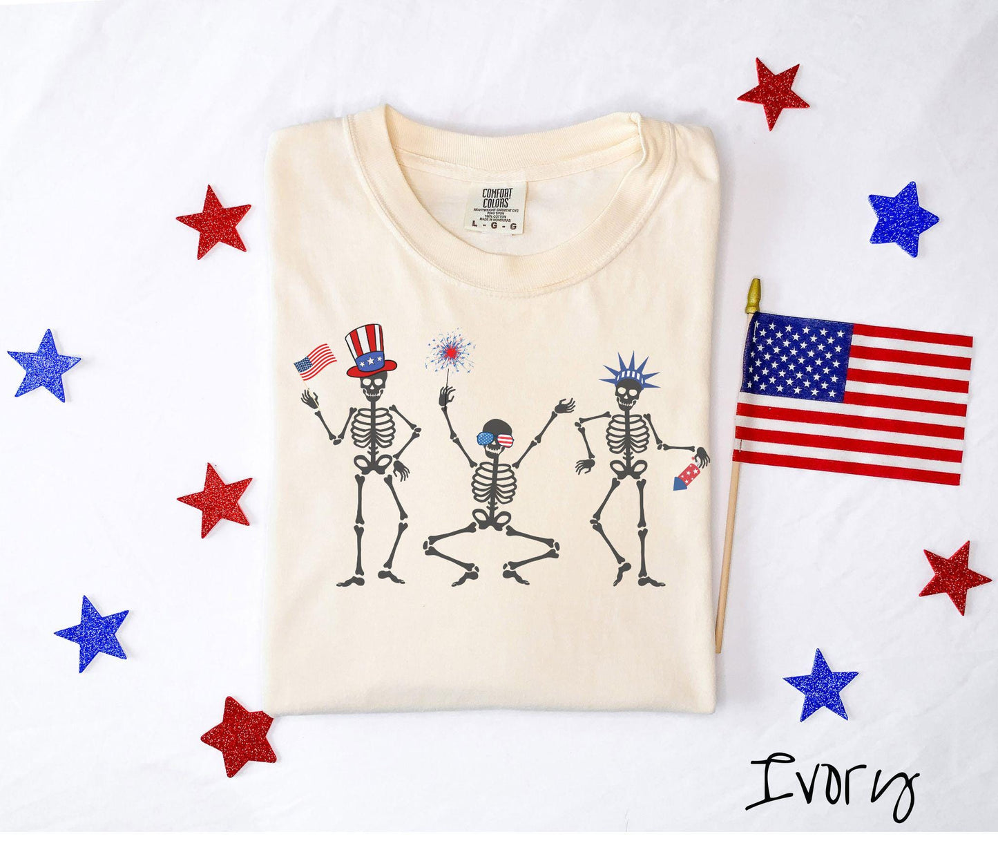 Celebrate in style with this vintage-inspired tee featuring three dancing skeletons decked out in red, white, and blue hats. They hold American flags, sparklers, and fireworks, making it the perfect shirt for Fourth of July celebrations.