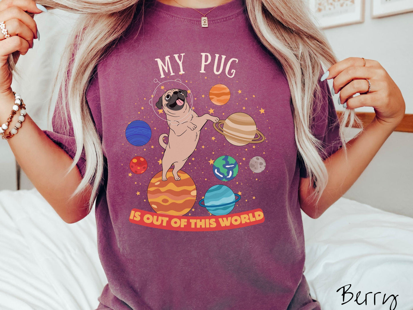 A vintage Comfort Colors t-shirt featuring the text My Pug is Out of This World. The design showcases an adorable Pug sitting proudly atop Jupiter, surrounded by a vibrant solar system filled with colorful planets and twinkling stars.