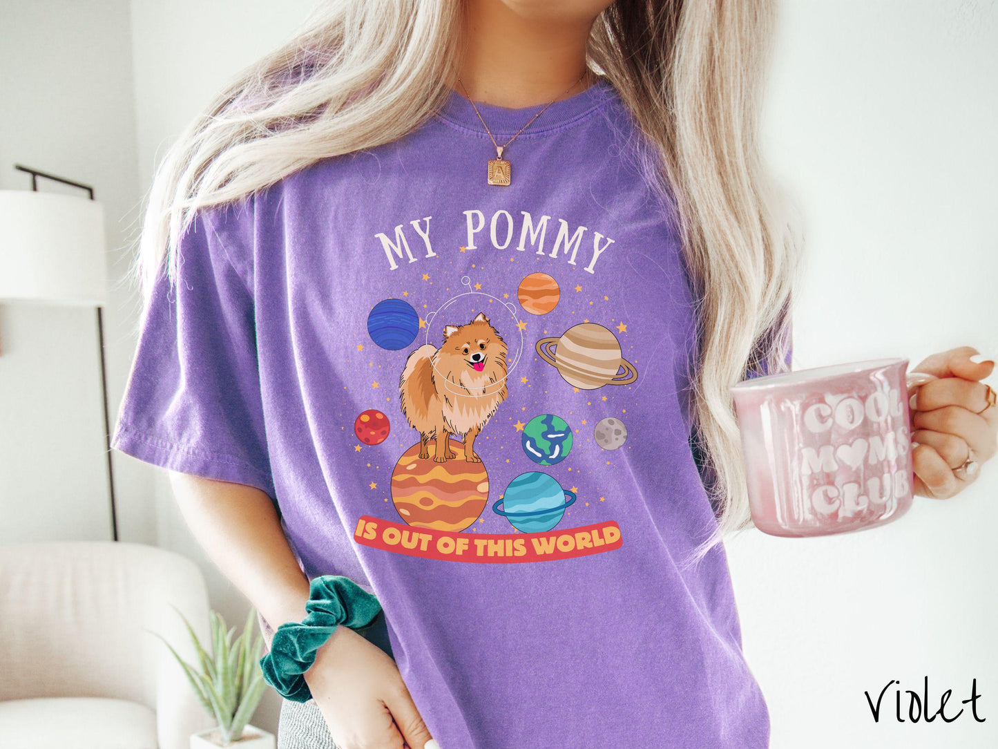 A vintage Comfort Colors t-shirt featuring the text My Pomeranian is Out of This World. The design showcases an adorable Pomeranian sitting proudly atop Jupiter, surrounded by a vibrant solar system filled with colorful planets and twinkling stars.