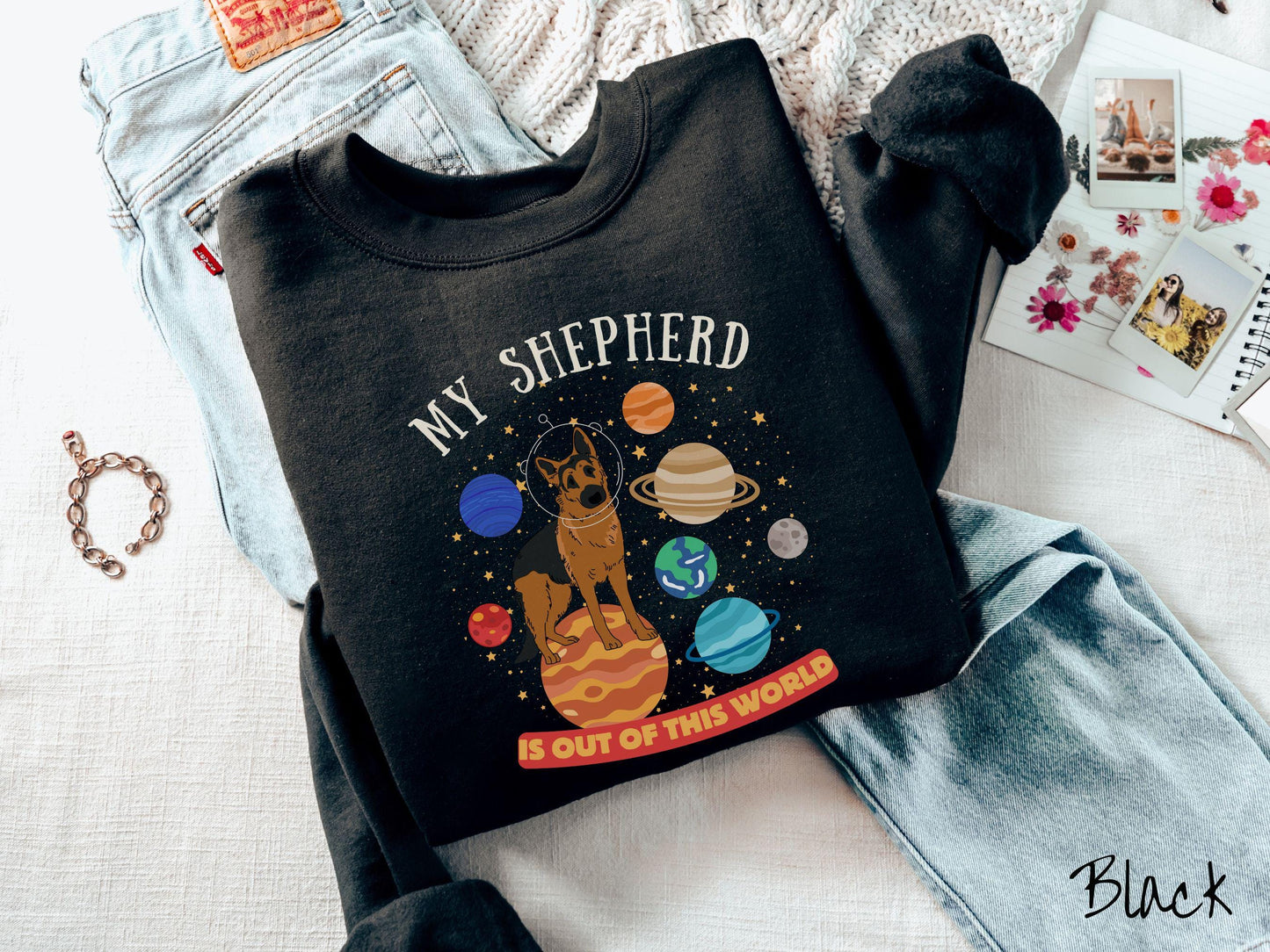 A vintage Gildan sweatshirt featuring the text My Shepherd is Out of This World. The design showcases a German Shepherd sitting proudly atop Jupiter, surrounded by a vibrant solar system filled with colorful planets and twinkling stars.