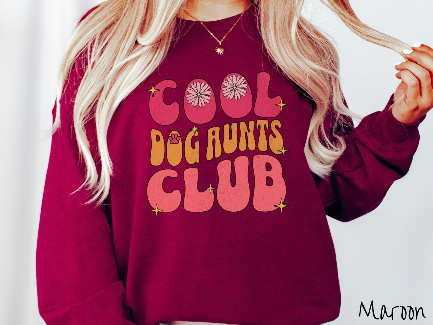 A vintage Gildan sweatshirt featuring the text "Cool Dog Aunts Club" in bold red, yellow, and orange fonts with flower petals nestled in the "O" of COOL, a cute red paw print in the "O" of DOG, and sparkling yellow stars throughout.