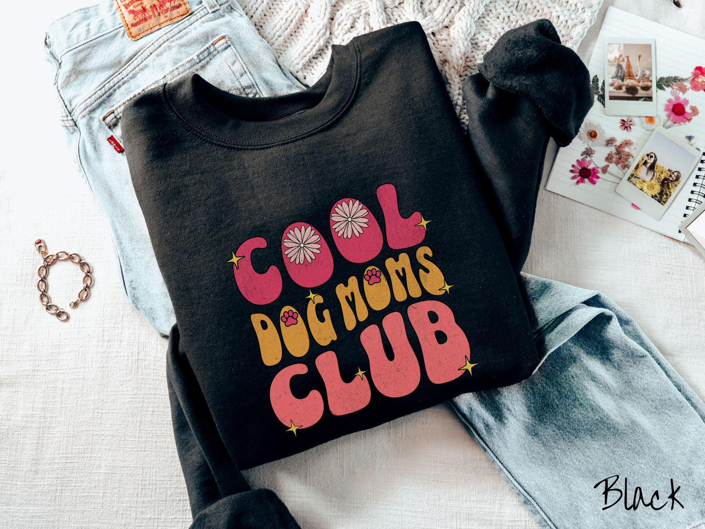 A vintage Gildan sweatshirt featuring the playful text Cool Dog Moms Club, this design is full of charming details. From flower petals nestled in the "O" of COOL to a cute red paw print in the "O" of DOG and sparkling yellow stars throughout.