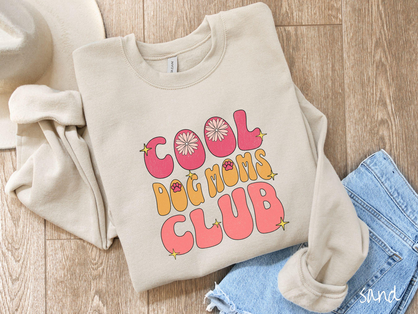 A vintage Gildan sweatshirt featuring the playful text Cool Dog Moms Club, this design is full of charming details. From flower petals nestled in the "O" of COOL to a cute red paw print in the "O" of DOG and sparkling yellow stars throughout.