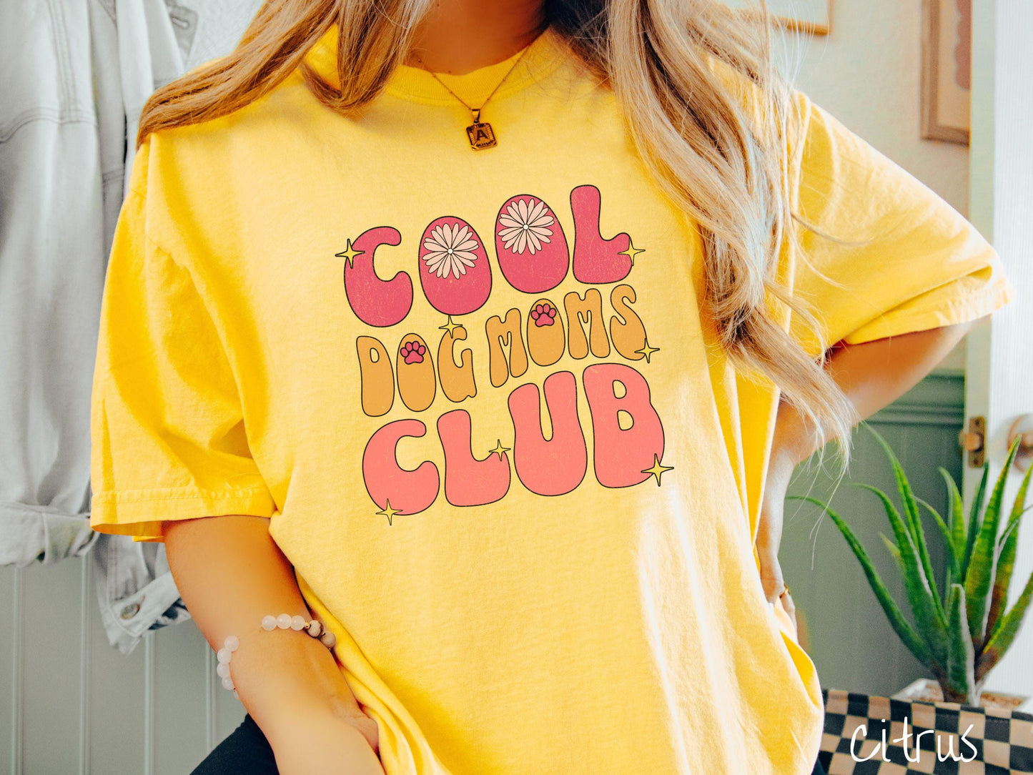 A vintage Comfort Colors t-shirt featuring the playful text Cool Dog Moms Club, this design is full of charming details. From flower petals nestled in the "O" of COOL to a cute red paw print in the "O" of DOG and sparkling yellow stars throughout.