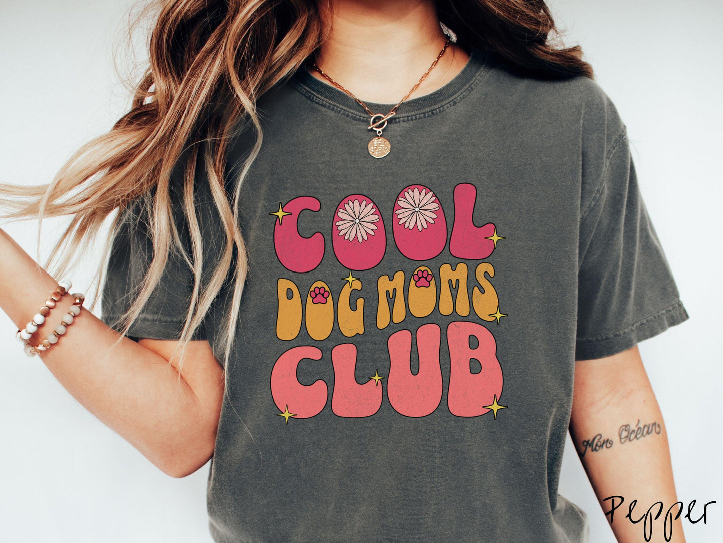 A vintage Comfort Colors t-shirt featuring the playful text Cool Dog Moms Club, this design is full of charming details. From flower petals nestled in the "O" of COOL to a cute red paw print in the "O" of DOG and sparkling yellow stars throughout.