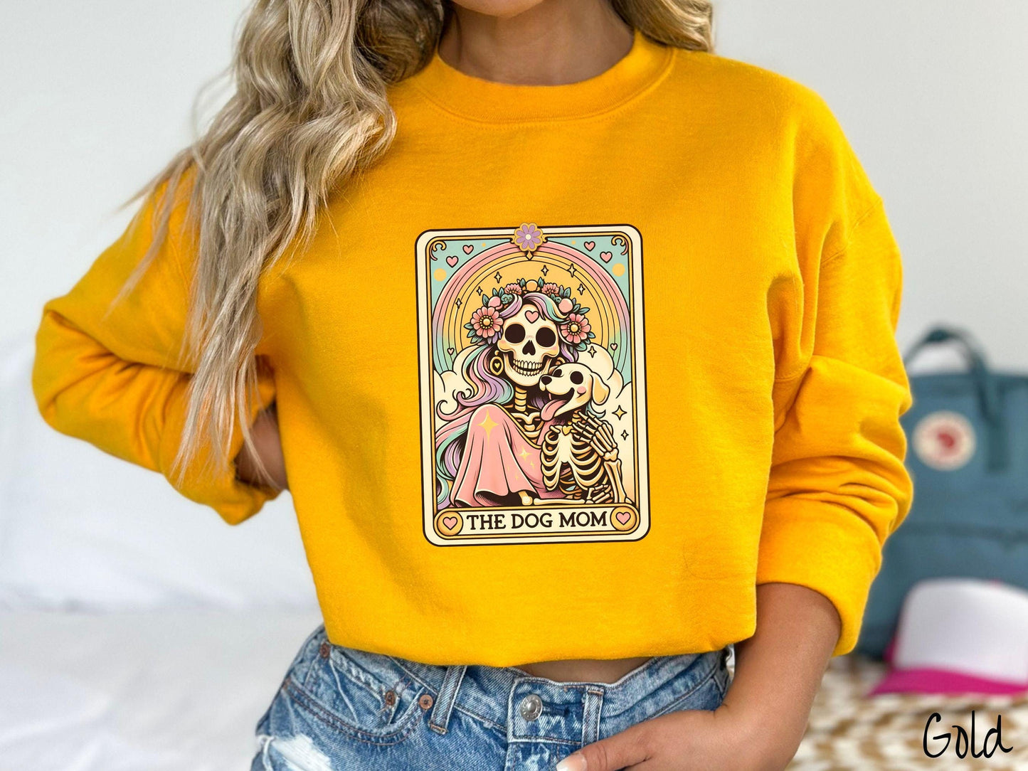 A vintage Gildan sweatshirt features a tarot card design with the text “The Dog Mom” along the bottom, framed by red hearts. Inside the tarot card is a female skeleton with flowing hair adorned with colorful flowers holding a skeleton dog.