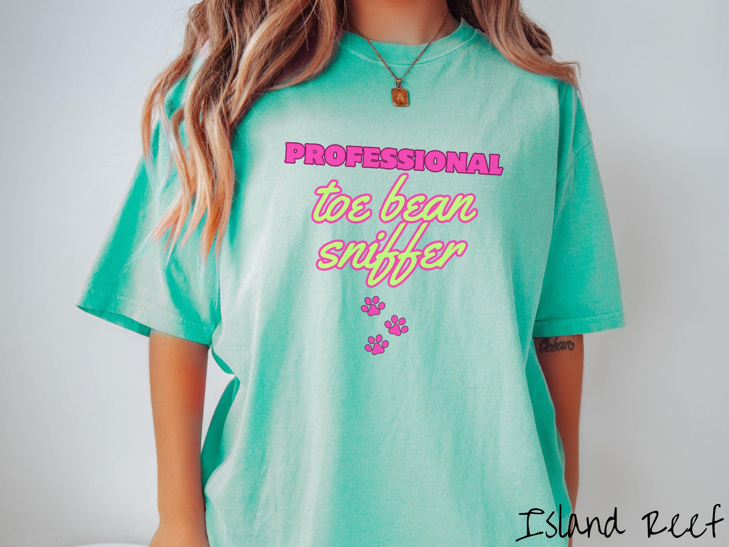 A vintage Comfort Colors t-shirt perfect for dog lovers who can’t resist those adorable toe beans! It features the funny text Professional Toe Bean Sniffer in bold pink and green fluorescent font, and below the text are three pink dog paw prints.