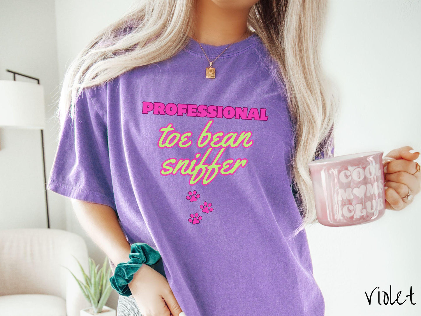 A vintage Comfort Colors t-shirt perfect for dog lovers who can’t resist those adorable toe beans! It features the funny text Professional Toe Bean Sniffer in bold pink and green fluorescent font, and below the text are three pink dog paw prints.