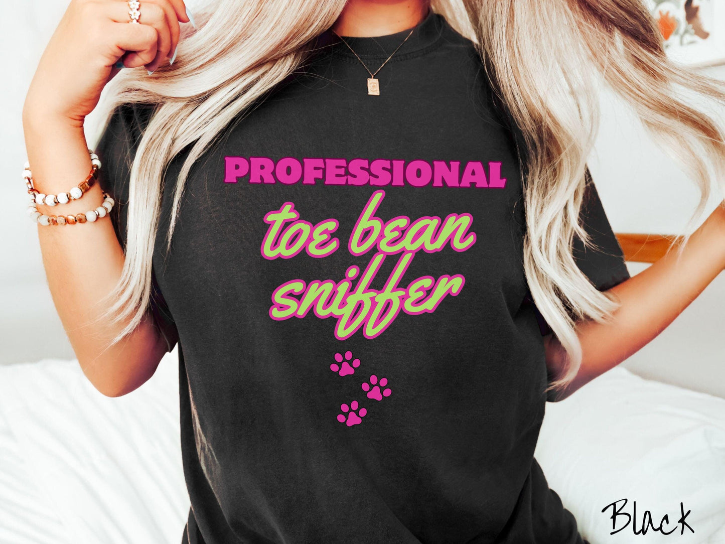 A vintage Comfort Colors t-shirt perfect for dog lovers who can’t resist those adorable toe beans! It features the funny text Professional Toe Bean Sniffer in bold pink and green fluorescent font, and below the text are three pink dog paw prints.