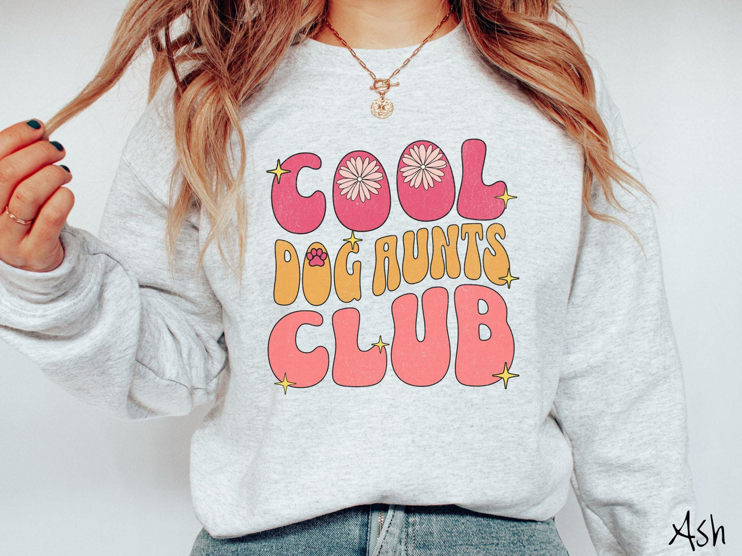 A vintage Gildan sweatshirt featuring the text "Cool Dog Aunts Club" in bold red, yellow, and orange fonts with flower petals nestled in the "O" of COOL, a cute red paw print in the "O" of DOG, and sparkling yellow stars throughout.
