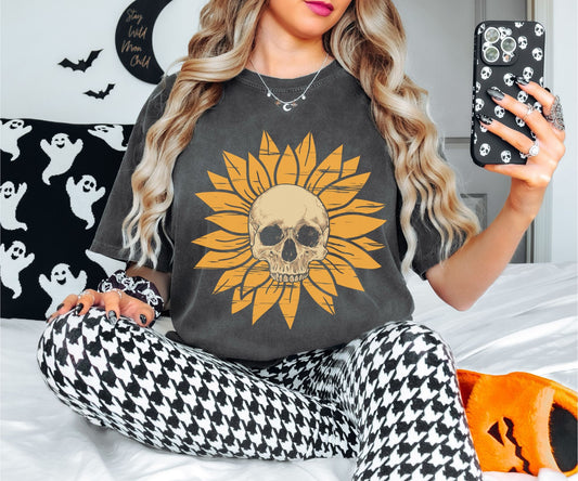 A woman wearing a cute pepper colored shirt with a light yellow skull in the middle of a yellow sunflower.