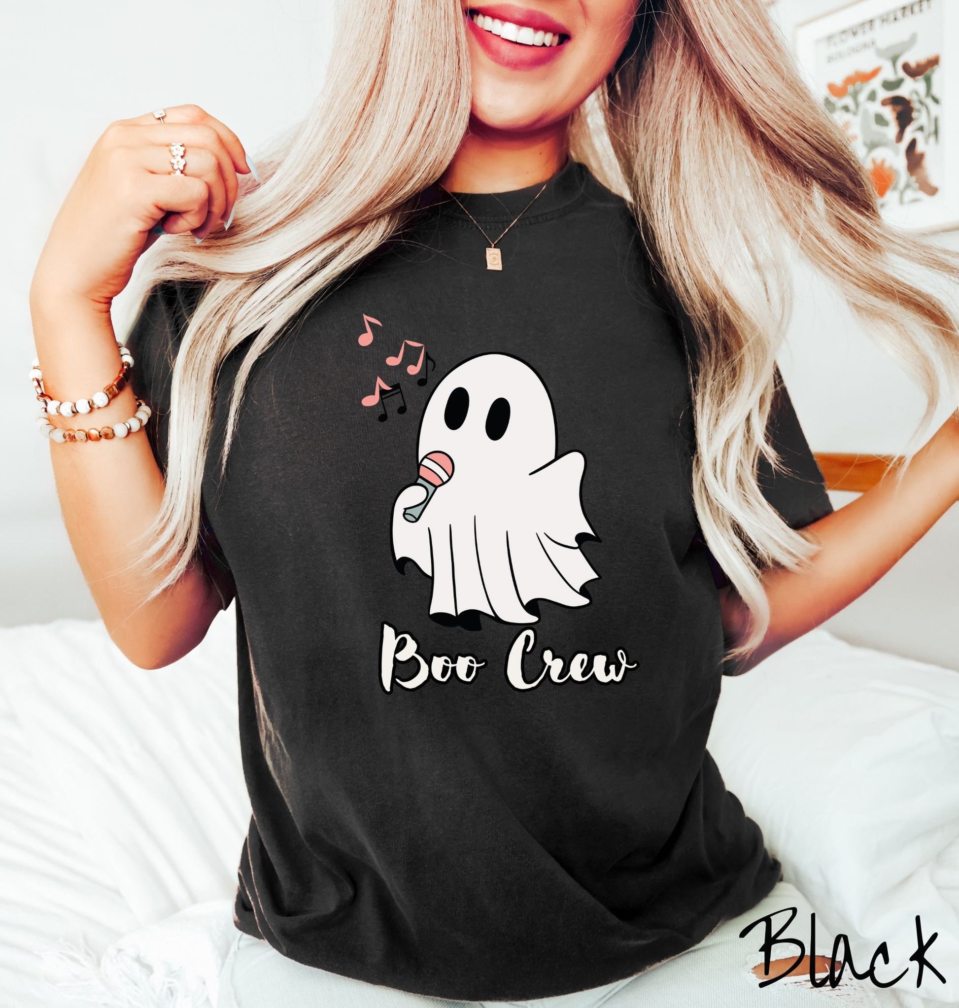 A woman wearing a cute black colored shirt with the text Boo Crew under a ghost figure holding a camera.