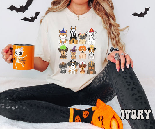 A woman wearing a cute, vintage ivory colored Comfort Colors t-shirt with a four by three grid of different breeds of dogs dressed up in Halloween costumes. There is a dog dressed as a fireman and another as a nurse among others.