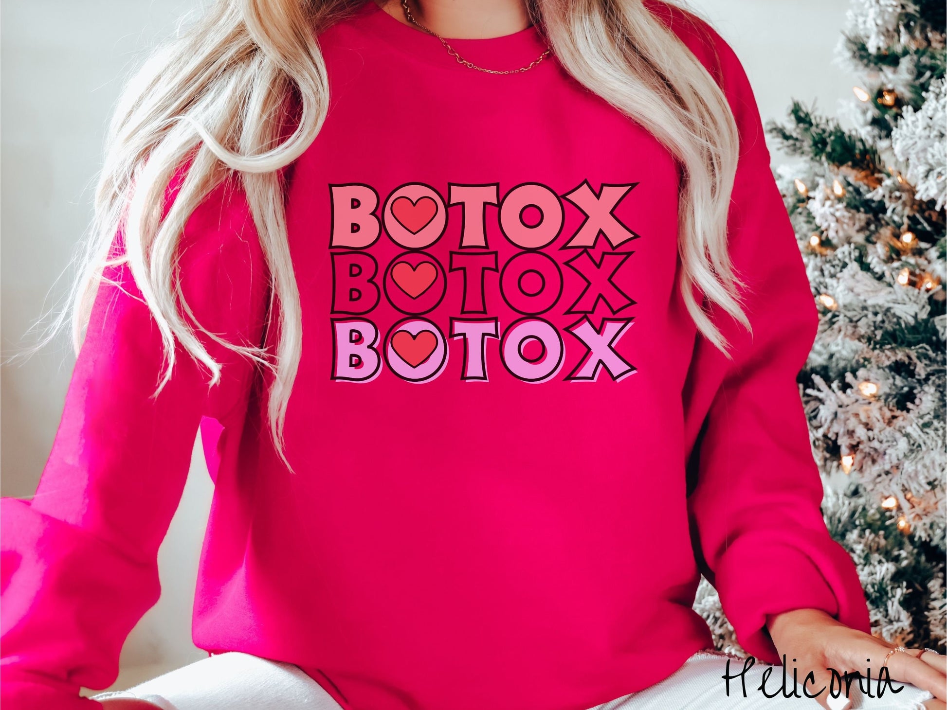 A woman wearing a cute heliconia colored sweatshirt with the word Botox listed three times in different shades of pink and red, with red hearts inside the first letter O in Botox.