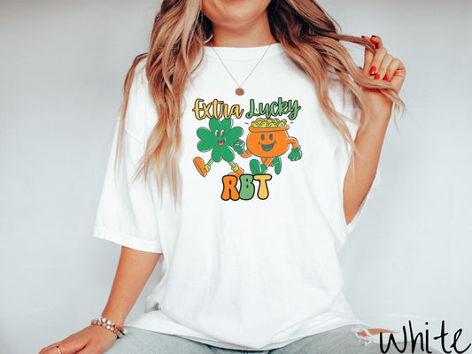 A woman wearing a vintage, white colored shirt with the text Extra Lucky RBT  in yellow, orange, and green font. Between the text are a green clover and orange pot of gold smiling and walking together in step.