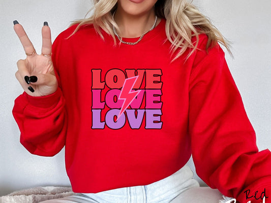 A woman wearing a cute, vintage red colored sweatshirt with the word Love listed three times vertically with a pink lightning bolt going through the middle of the words.