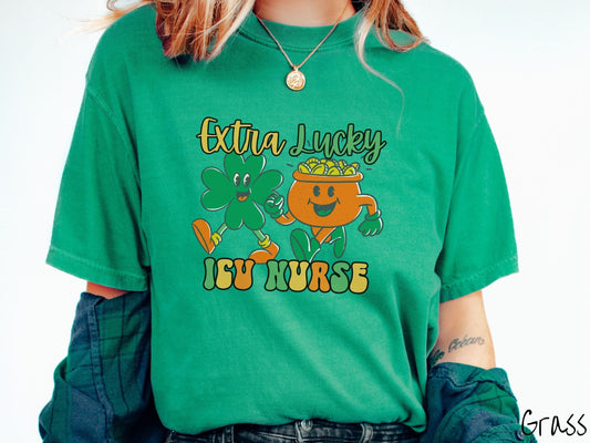 A woman wearing a vintage, grass colored shirt with the text Extra Lucky ICU Nurse in yellow, orange, and green font. Between the text are a green clover and orange pot of gold smiling and walking together in step.