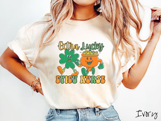 A woman wearing a vintage, ivory colored shirt with the text Extra Lucky CVICU Nurse in yellow, orange, and green font. Between the text are a green clover and orange pot of gold smiling and walking together in step.