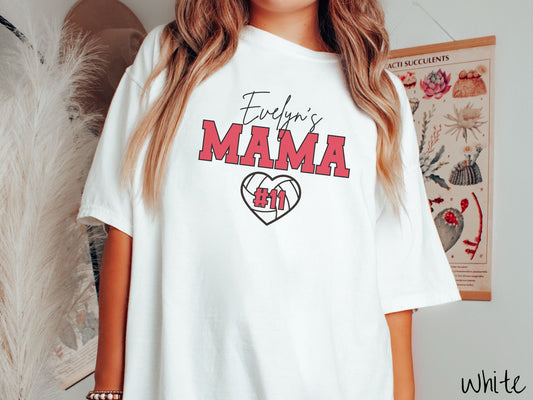A woman wearing a cute white colored t-shirt with black and red text saying Evelyns Mama. Below is a black, heart-shaped volleyball outline with #11 in red font written across it.
