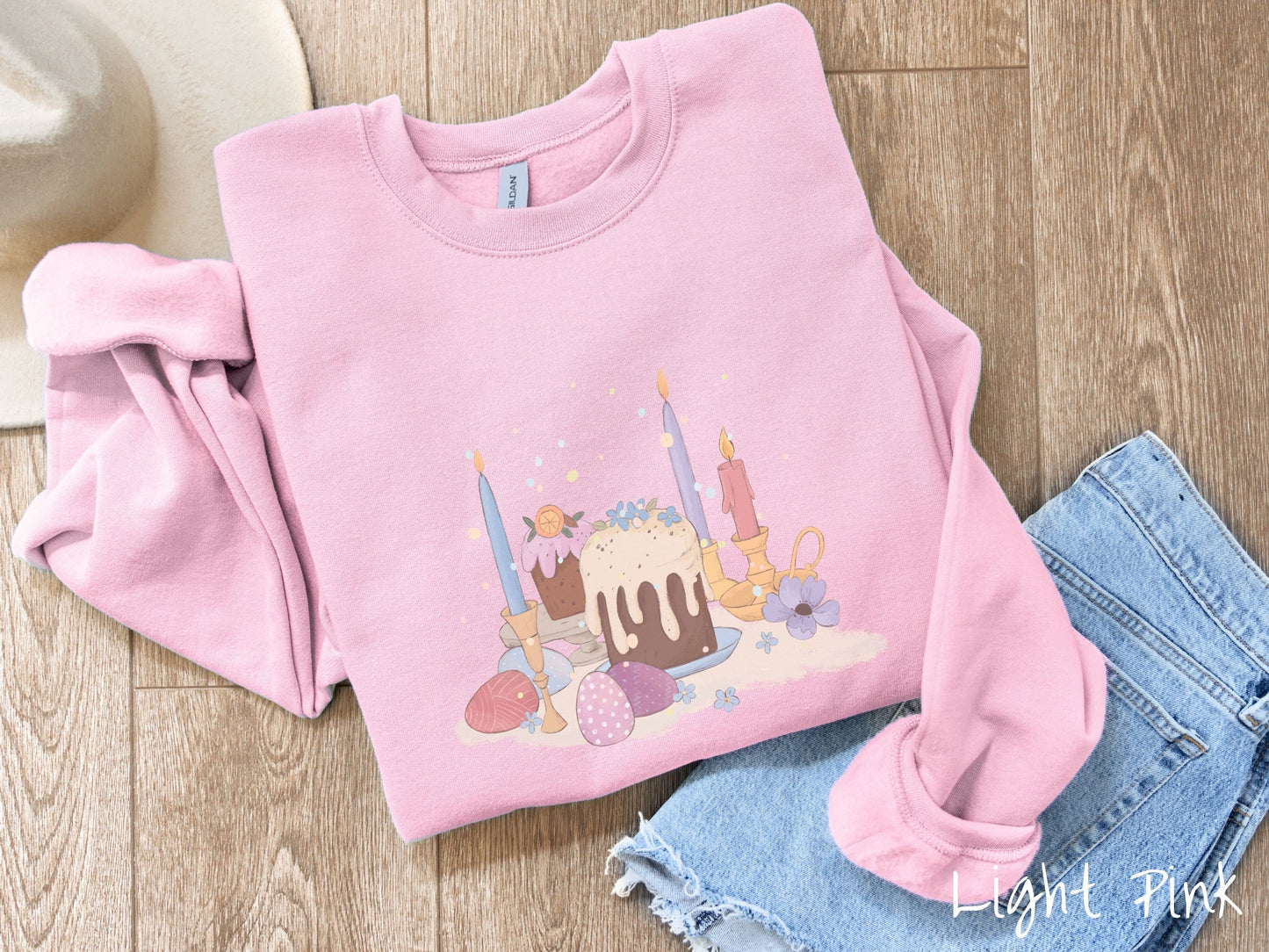 A cute, vintage light pink colored sweatshirt with an assortment of colorful candles with wax running down the sides in the center, scattered around the candles are pink, purple, red, and blue colored Easter eggs.