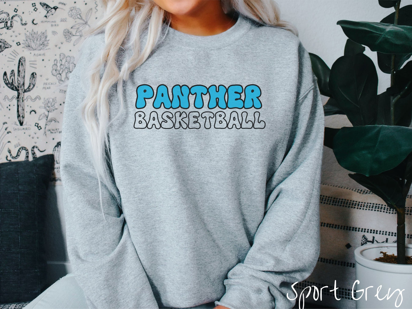 A woman wearing a cute, vintage sport grey colored sweatshirt with the word Panther across the front in blue, uppercase font. Below that is the word Basketball in gray, uppercase font.