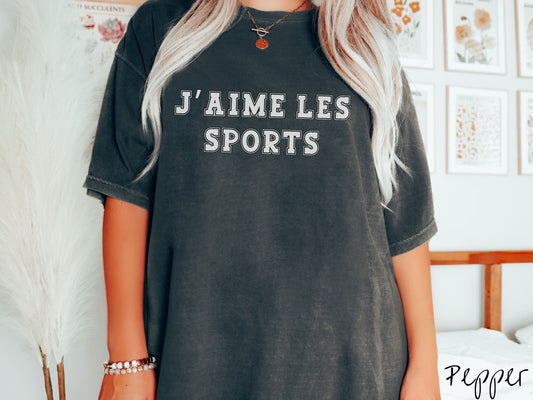 A woman wearing a cute, vintage pepper colored shirt with the text J’ Aime Les Sports in white font across the front.