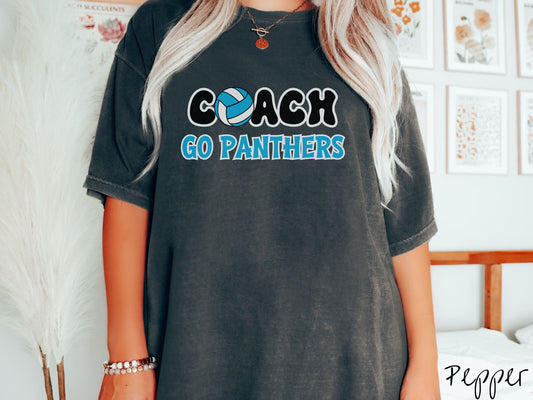 A woman wearing a cute pepper colored t-shirt with the word Coach in black and white font, the O in Coach is a blue and white volleyball. Below Coach are the words in blue and white font Go Panthers.