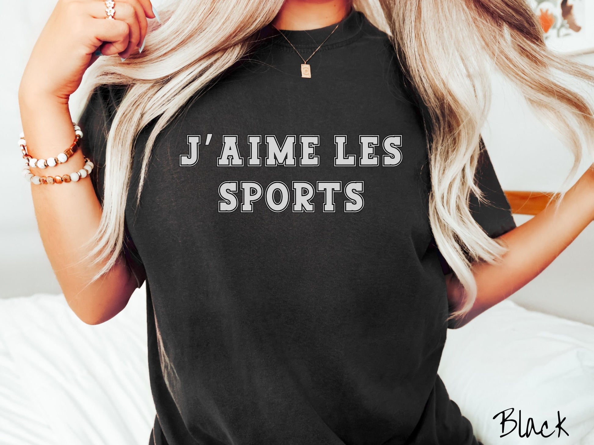 A woman wearing a cute, vintage black colored shirt with the text J’ Aime Les Sports in white font across the front.