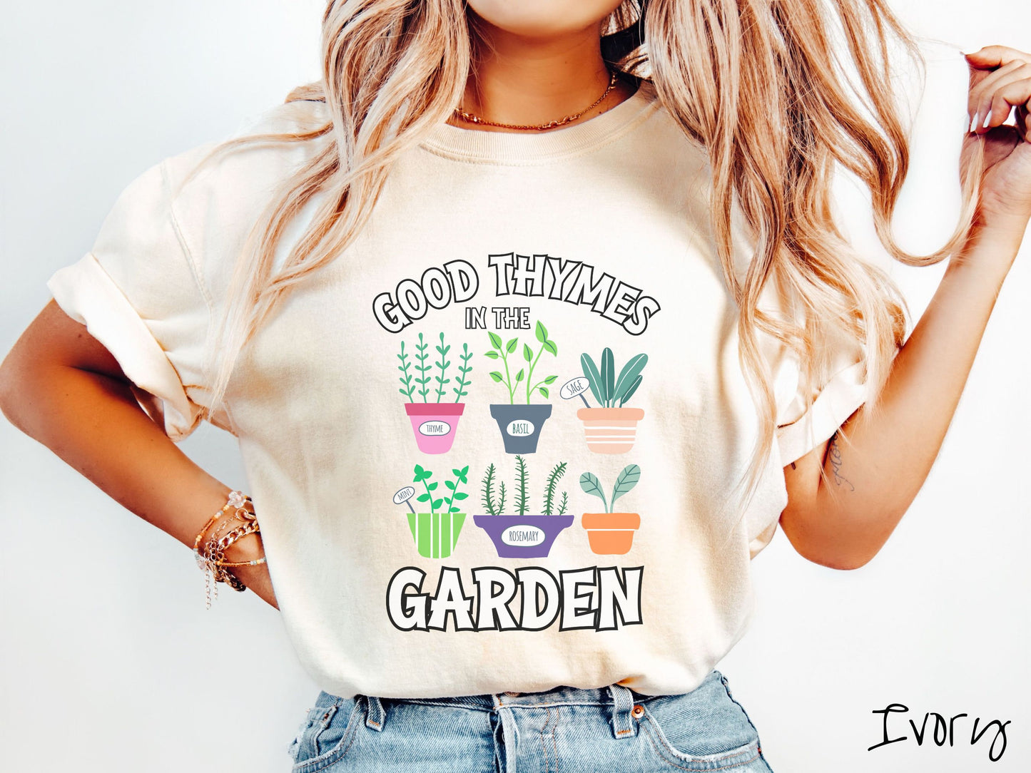 A woman wearing a cute, vintage ivory colored Comfort Colors t-shirt with the text Good Thymes in the Garden in white font. In between the text are different potted vegetables in colorful pots like thyme, basil, sage, and mint.