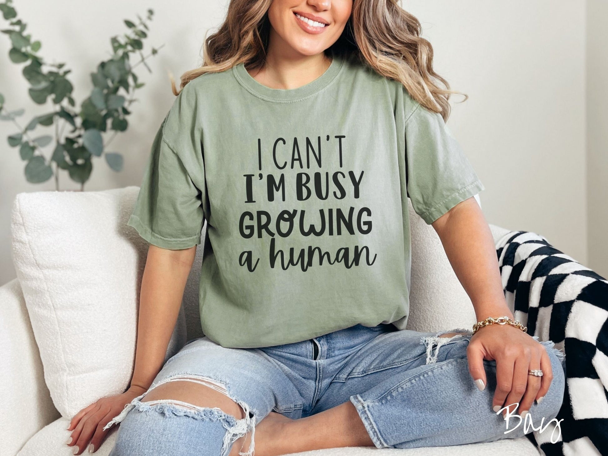A woman wearing a vintage, bay colored Comfort Colors t-shirt with the text in white font I Can’t I’m Busy Growing A Human.