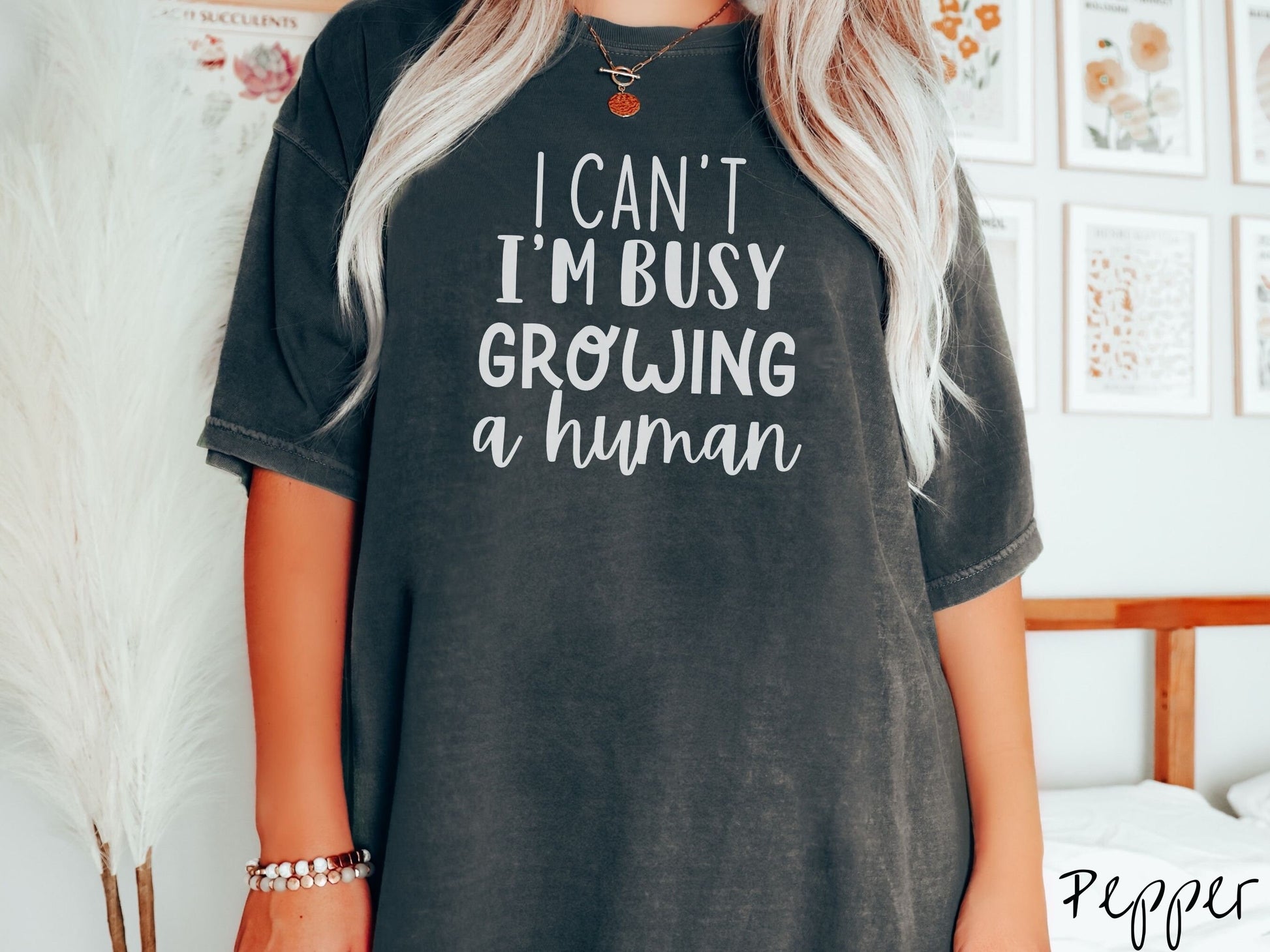 A woman wearing a vintage, pepper colored Comfort Colors t-shirt with the text in white font I Can’t I’m Busy Growing A Human.