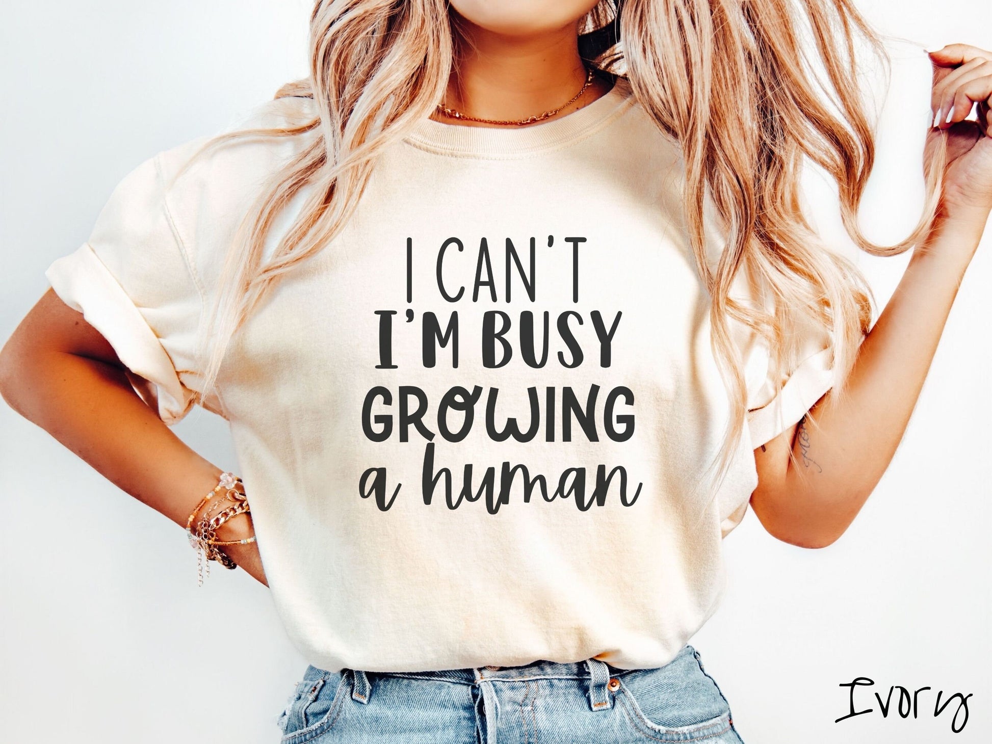 A woman wearing a vintage, ivory colored Comfort Colors t-shirt with the text in white font I Can’t I’m Busy Growing A Human.