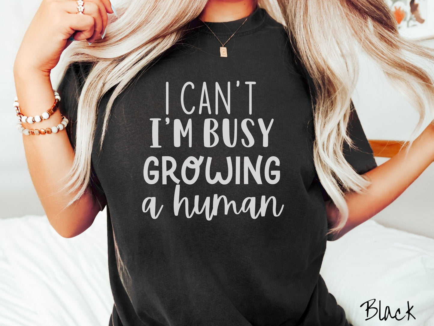 A woman wearing a vintage, black colored Comfort Colors t-shirt with the text in white font I Can’t I’m Busy Growing A Human.