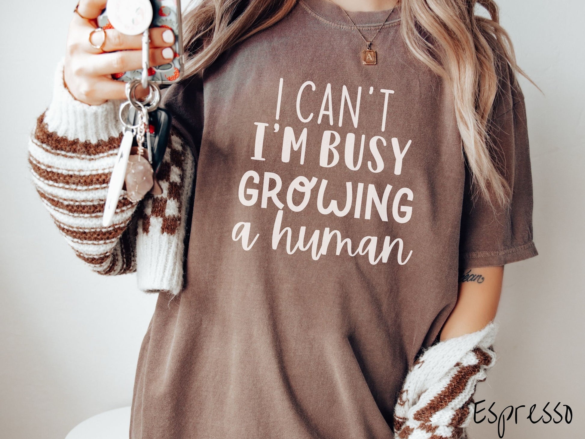 A woman wearing a vintage, espresso colored Comfort Colors t-shirt with the text in white font I Can’t I’m Busy Growing A Human.