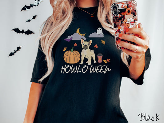 A woman wearing a vintage, black colored Comfort Colors t-shirt with the text Howl-O-Ween across the front. Above are a smiling French Bulldog, an orange pumpkin, a pumpkin-spiced latte, fall leaves, and a ghost and bat in the air.