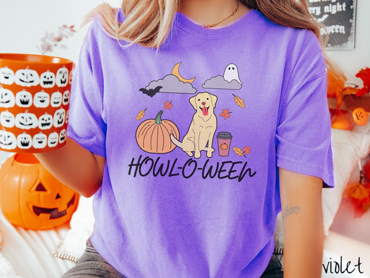 A woman wearing a vintage, violet colored Comfort Colors t-shirt with the text Howl-O-Ween across the front. Above are a smiling yellow lab dog, an orange pumpkin, a pumpkin-spiced latte, fall leaves, and a ghost and bat in the air.