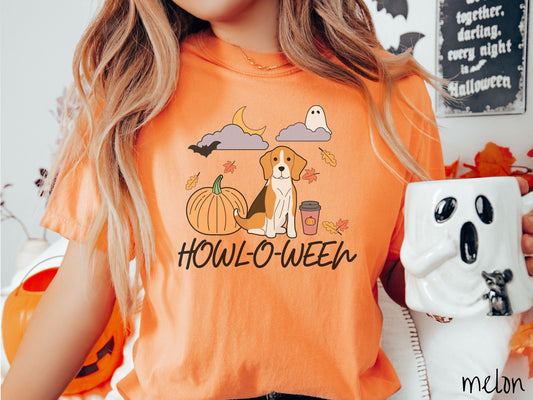 A woman wearing a vintage, melon colored Comfort Colors t-shirt with the text Howl-O-Ween across the front. Above are a smiling beagle hound dog, an orange pumpkin, a pumpkin-spiced latte, fall leaves, and a ghost and bat in the air.
