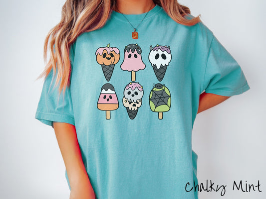 A woman wearing a cute, vintage chalky mint colored Comfort Colors T-shirt with a three by two grid of Halloween-themed, colorful ice cream cones. One has orange jack o&#39;lantern-esque ice cream, and another has candy corn-themed layered ice cream.