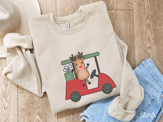 A woman wearing a cute sand colored sweatshirt with smiling reindeer driving a red golf cart and waving with both hands.